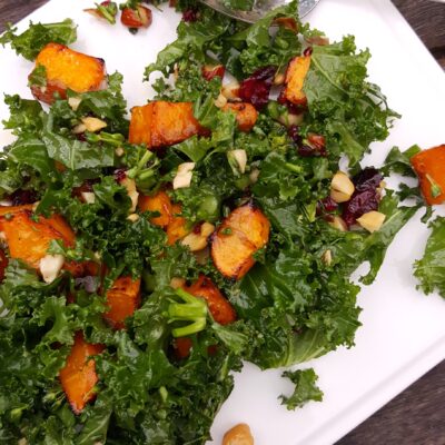 kale broccolini sweet potato salad on white plate with spoon