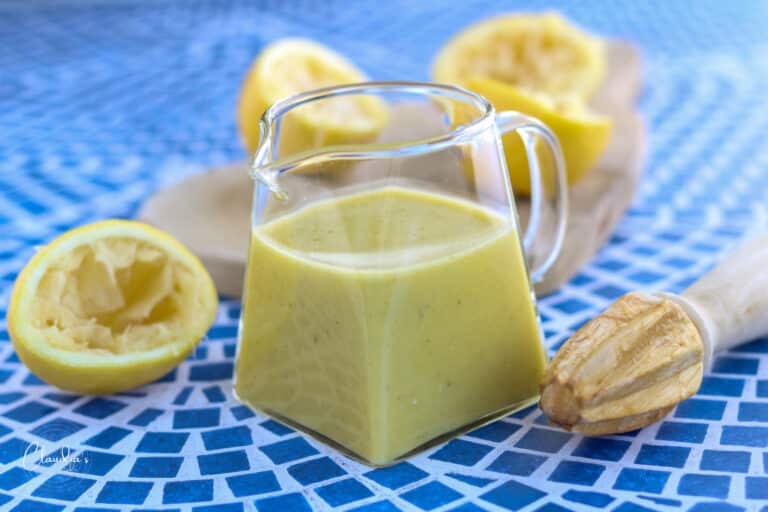 easy lemon dijon dressing on blue tiled table with fresh squeezed lemons