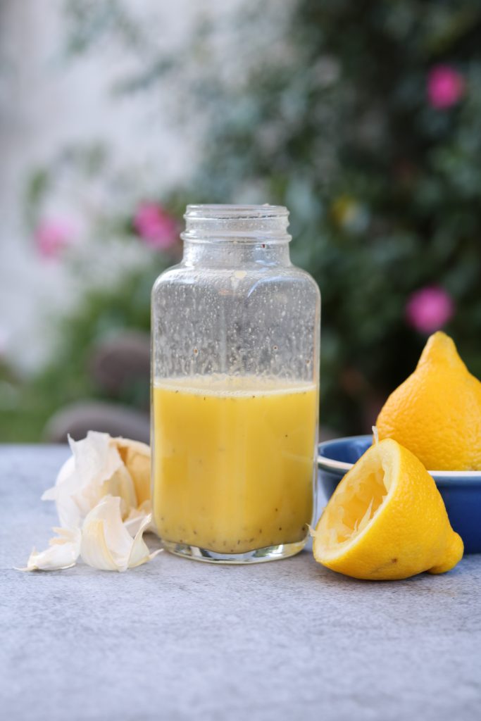 dressing in bottle with lemon and juicer on table outside