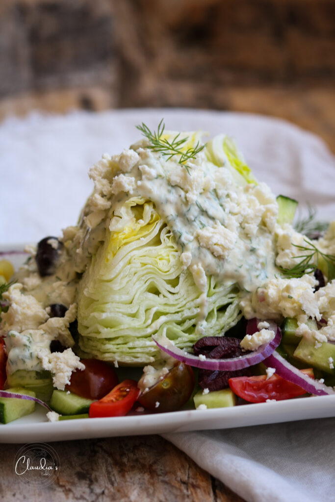 greek wedge salad on white plate with all the toppings