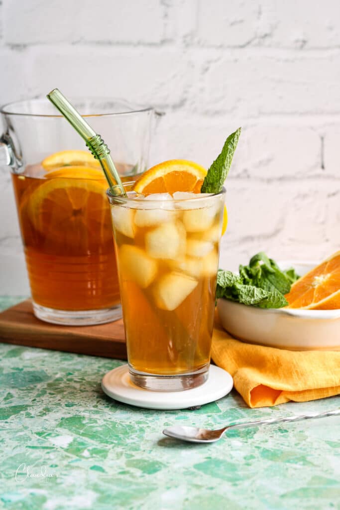 delicious glass of orange green tea in clear glass with green straw