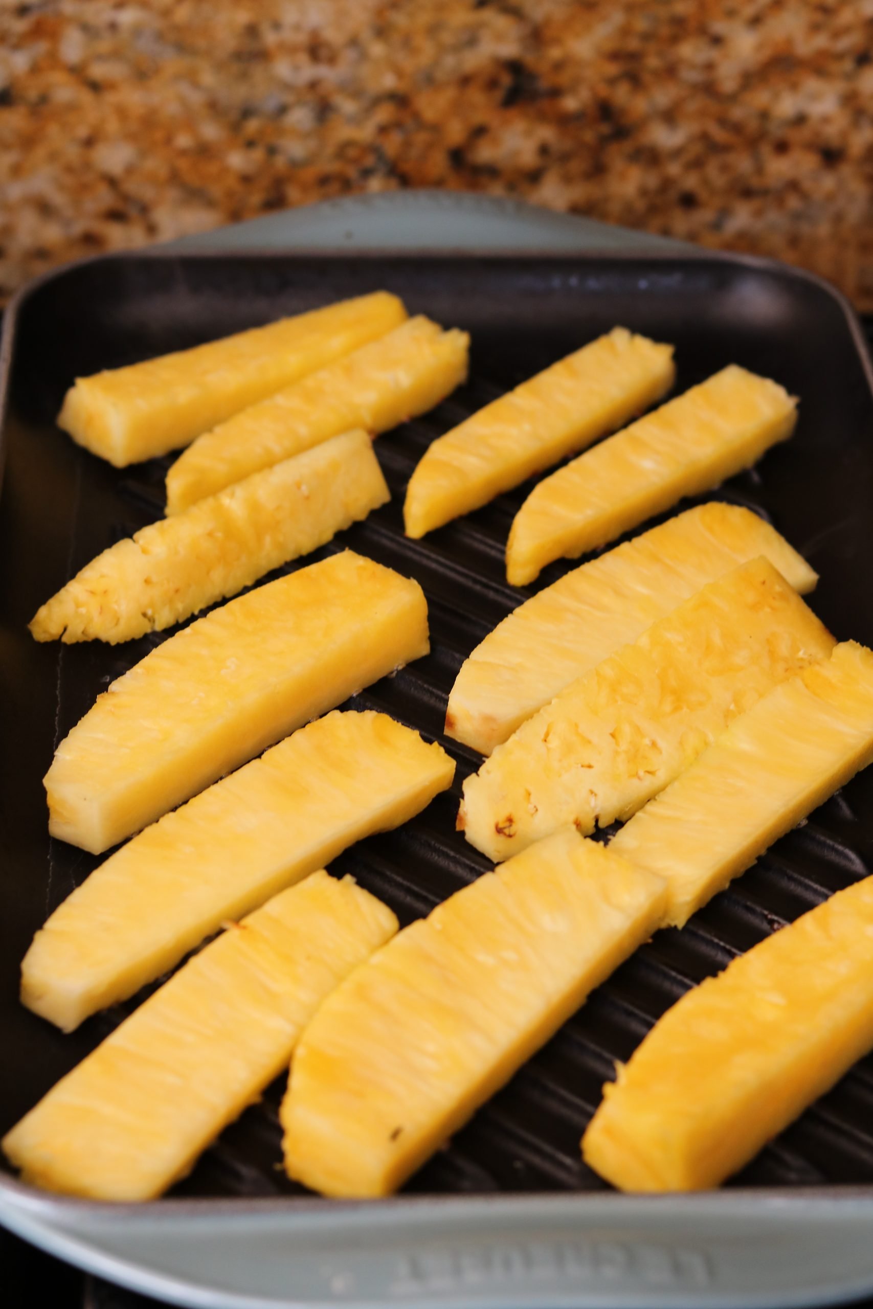 raw pineapple spears being grilled