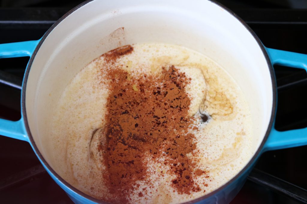 adding cinnamon and rum to ingredients to make spiced rum butter sauce 