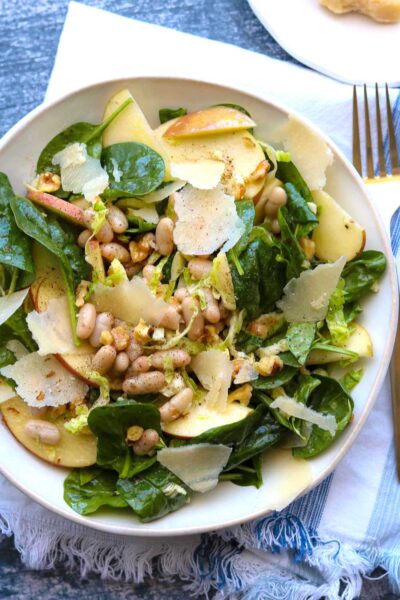 apple spinach white bean salad on plate with napkin and fork