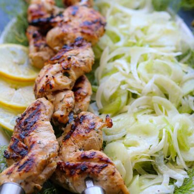 yogurt marinated chicken skewers, grilled with shaved fennel salad on platter with fennel fronds.
