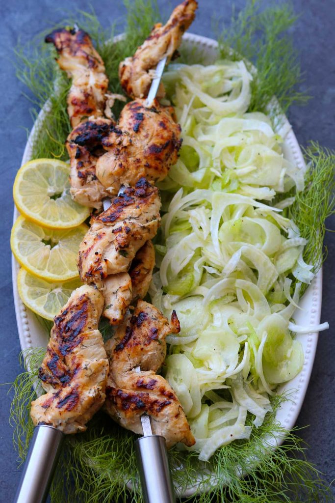yogurt herb marinated grilled chicken on skewers with shaved fennel salad on platter
