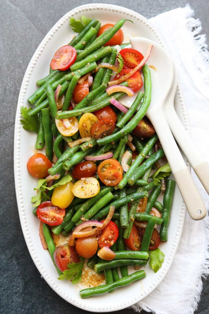 green bean tomato salad on serving platter with utensils