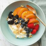 square image of summer fruit bowl with yogurt berries and peaches