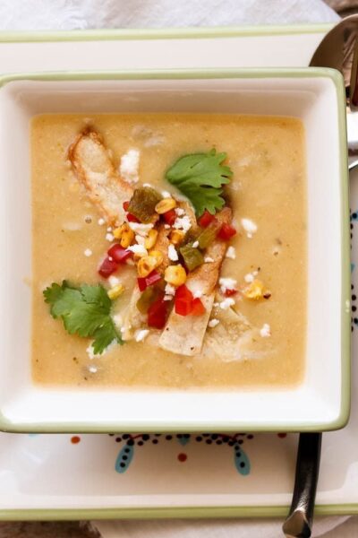 creamy potato hatch chile soup in square bowl with spoon and napkin