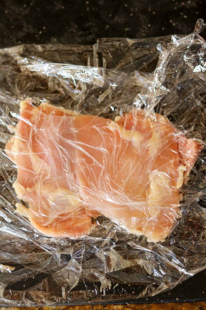 chicken between two pieces of plastic wrap pounded thin