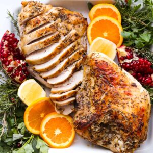 sliced and whole turkey breast with oranges and herbs square image