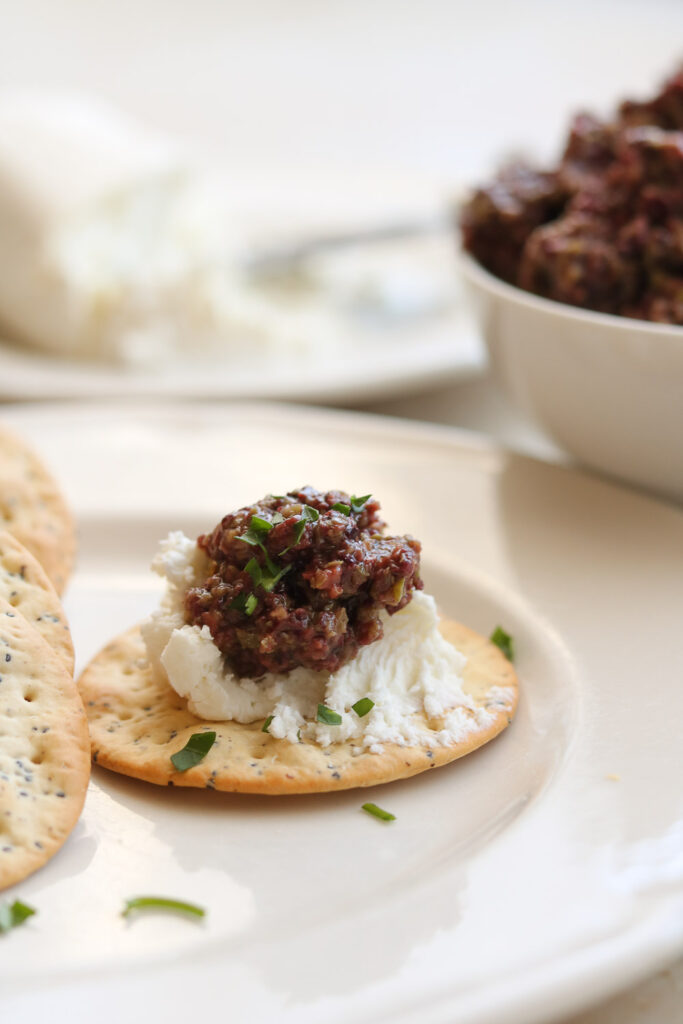 mixed olive tapenade on water  cracker with goat cheese 