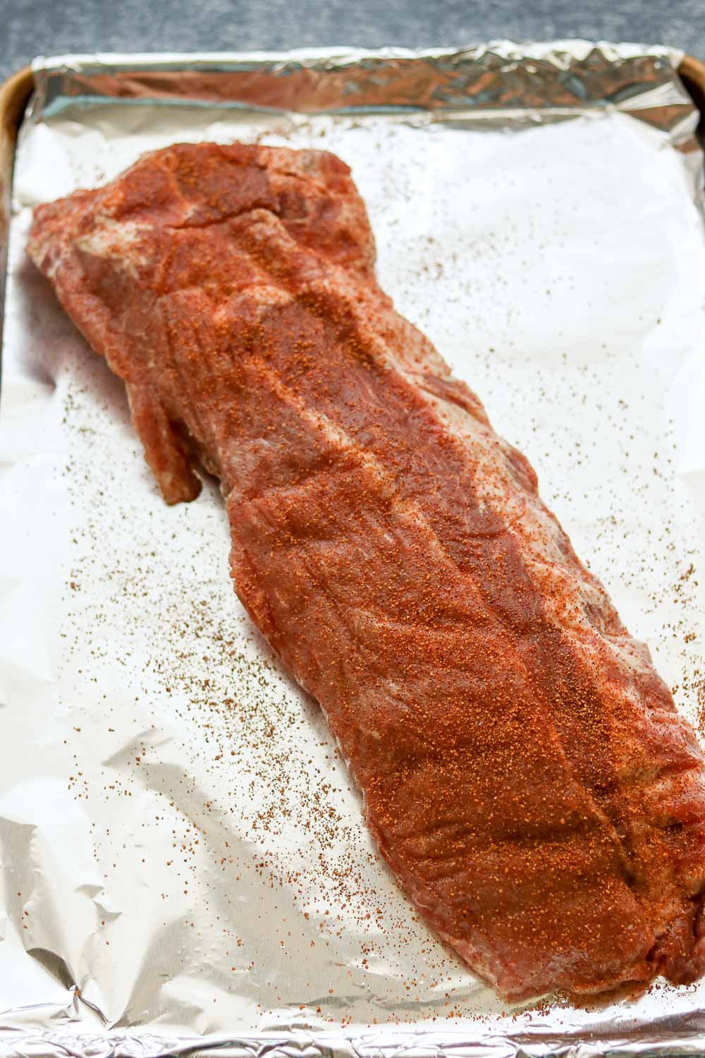 raw ribs with rub on half sheet with foil