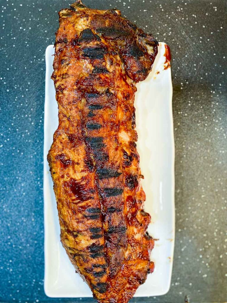 ribs cooked on bbq on platter with dark background 
