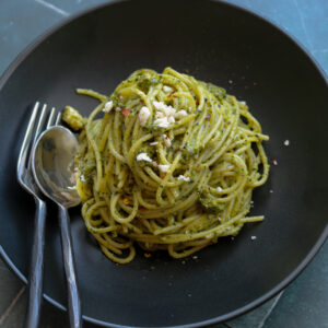 kale pistachio feta pesto on spaghetti in black bowl