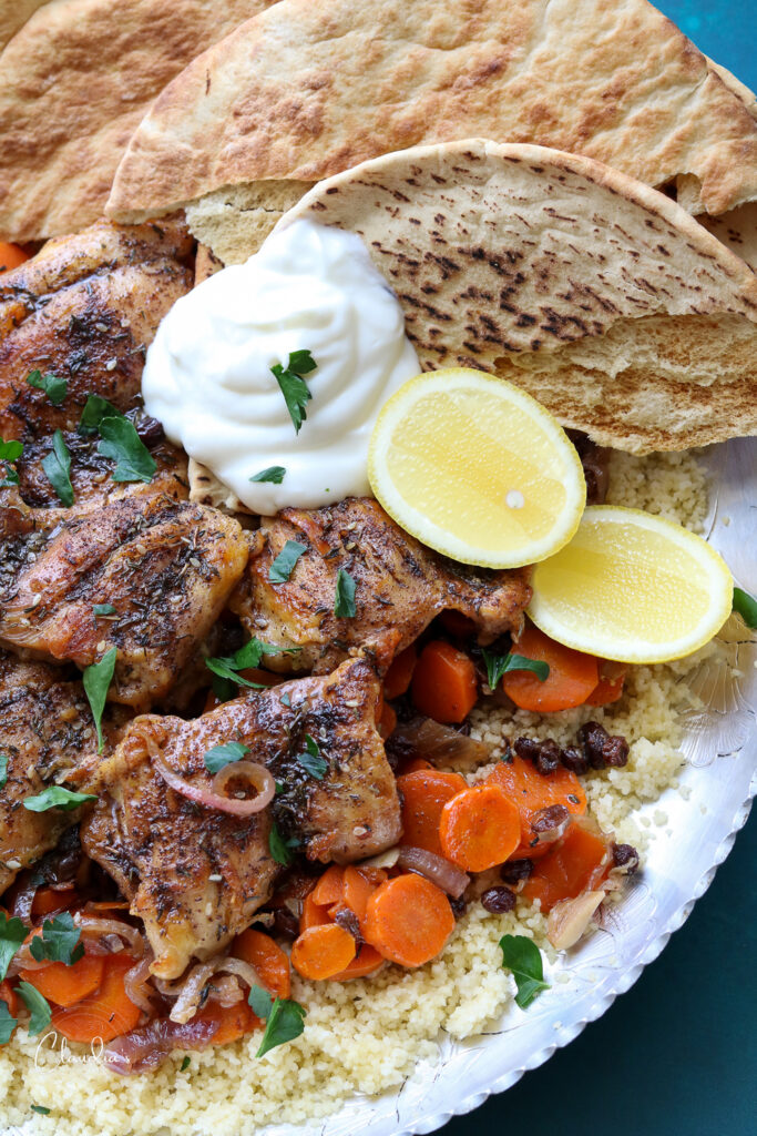 one plate chicken zaatar with carrots and currants with flatbread, yogurt and lemon wedges 