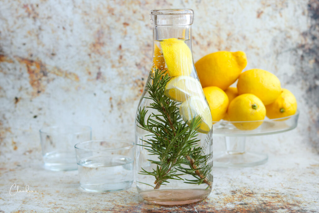 lemon rosemary water in carafe with lemons in the background