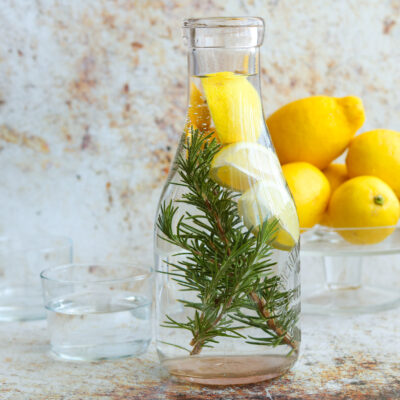 lemon rosemary water in carafe with lemons in the background