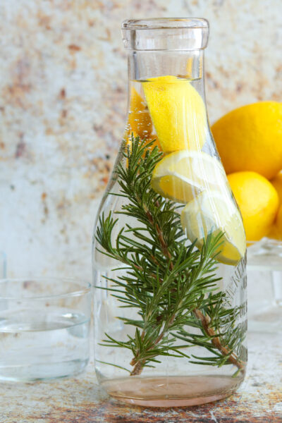 lemon rosemary water in carafe with lemons in the background