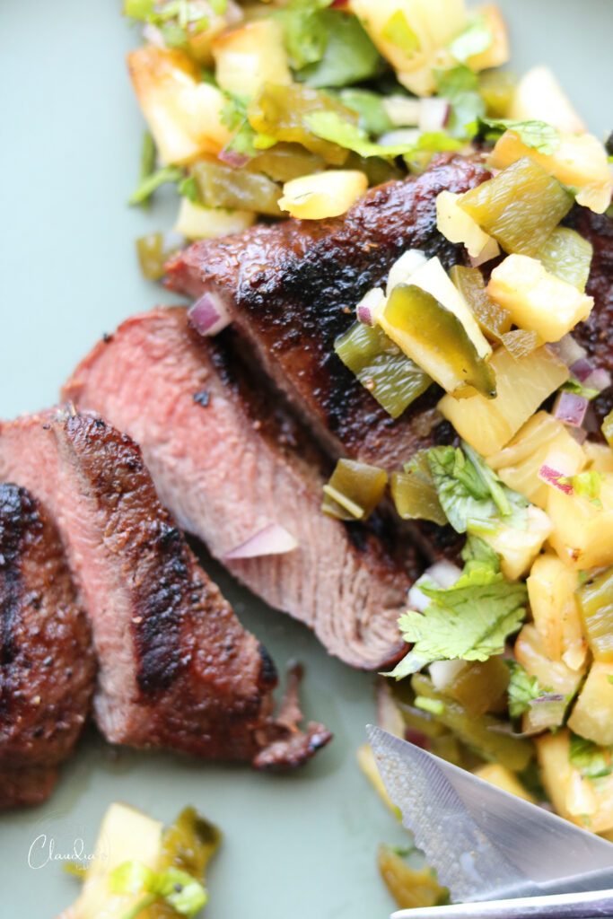 Chile rubbed steak with grilled pineapple jalapeño salsa on plate 