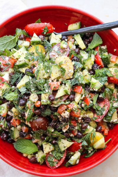 mediterranean chopped salad with feta in red bowl with spoon