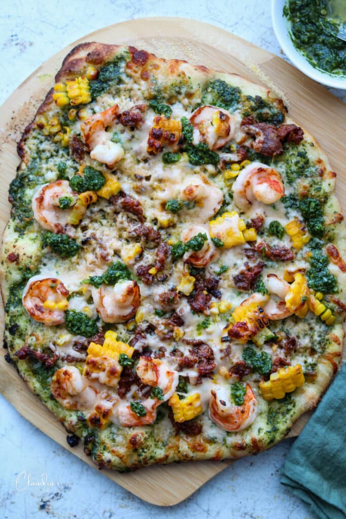 spicy chorizo shrimp pizza on pizza peel with jalapeno cilantro pesto.