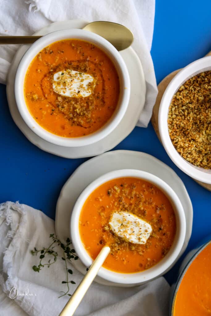 two bowls of roasted carrot and sweet potato soup with spoons 