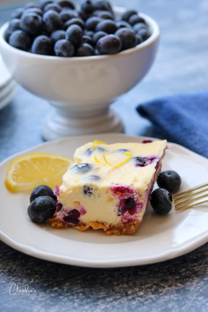 blueberry and lemon cheesecake bar on plate with blueberries