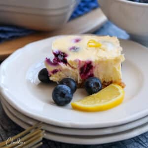 blueberry lemon cheesecake bar with fresh blueberries on white plate