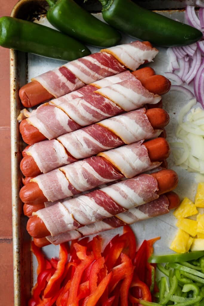 close up of bacon wrapped hot dogs on sheet pan 