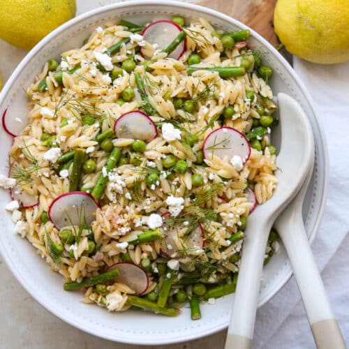 horizontal image of Orzo pasta salad with lemons in the background