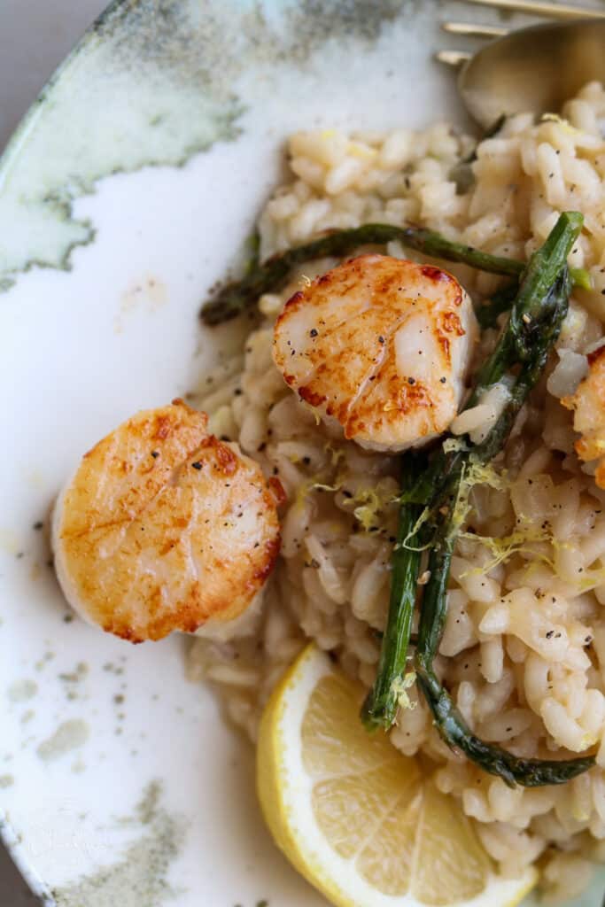 close up of creamy risotto, scallops, asparagus and lemon 