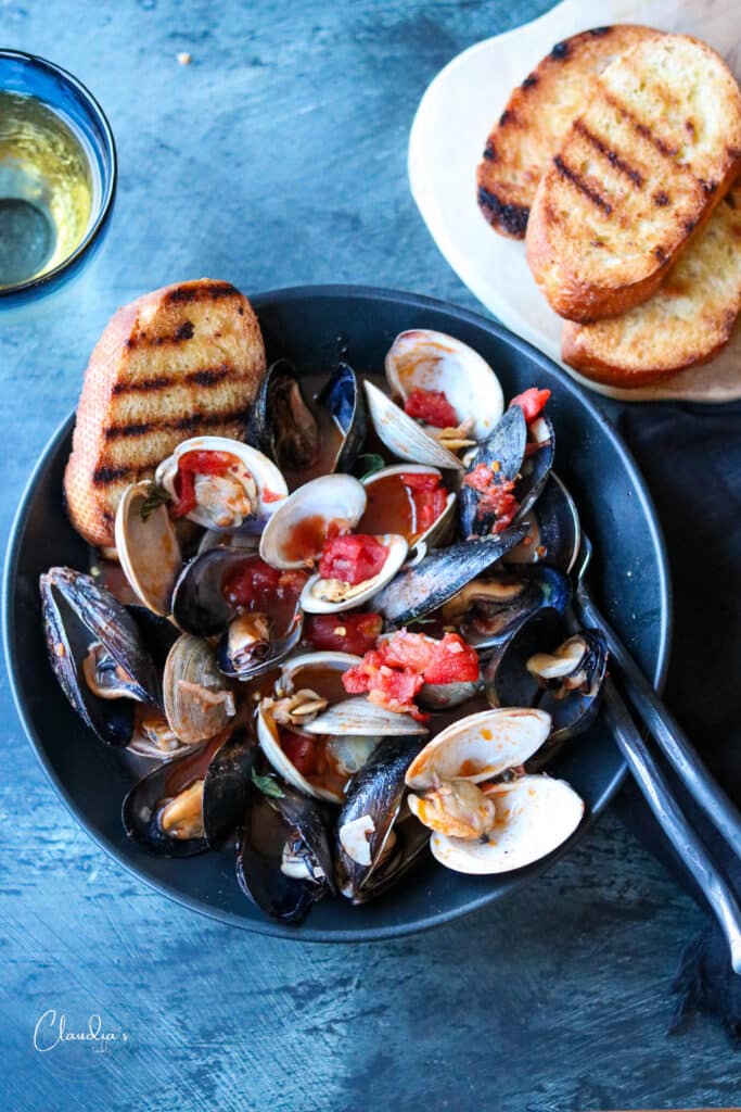 mussels and clams in black bowl with toasted bread 