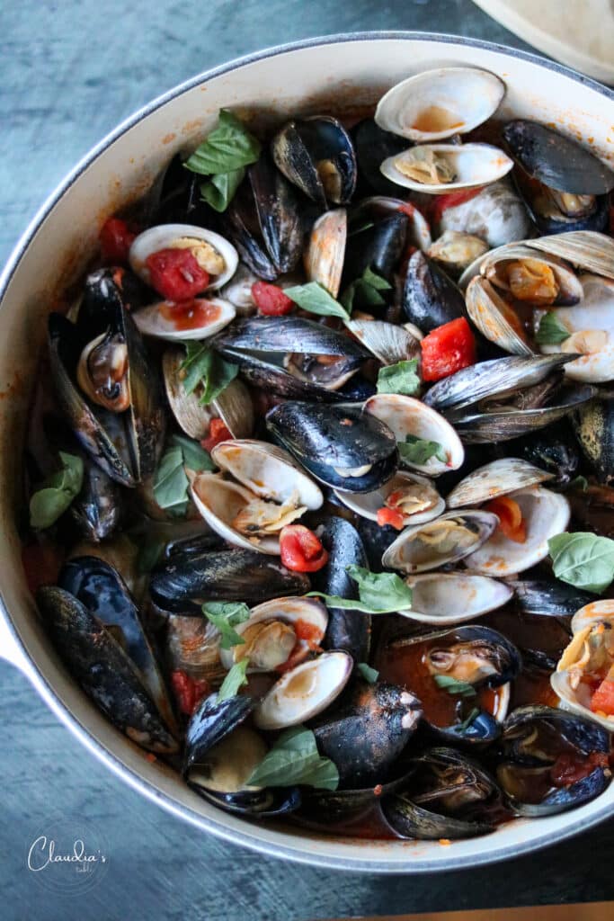 mussels and clams in tomato broth in dutch oven 