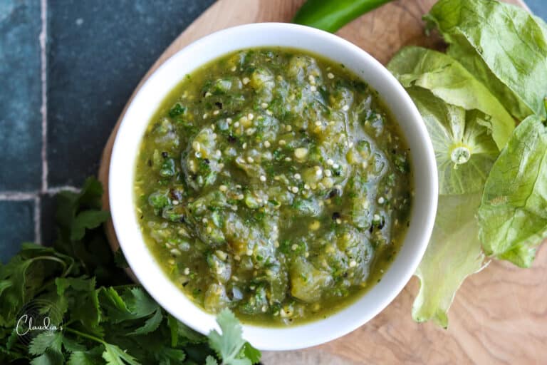 roasted tomatillo salsa verde on board with husks and cilantro