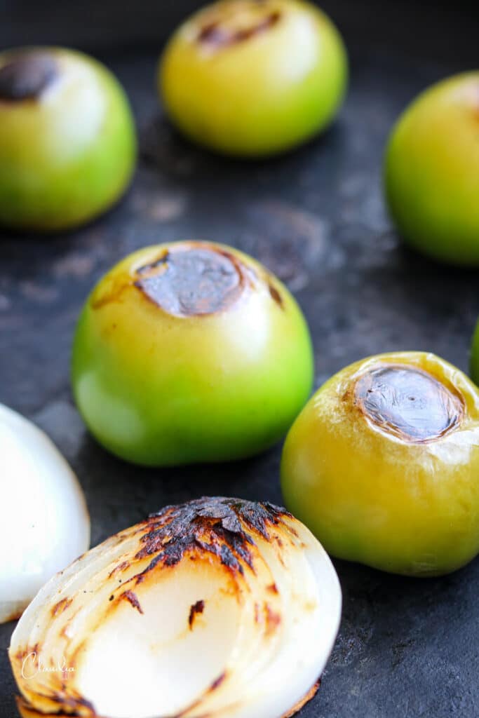 close up of tomatillos roasting in the cast iron pan