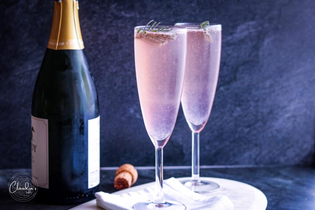 Lavender French 75 cocktail in champage flutes with sparkling wine in the background