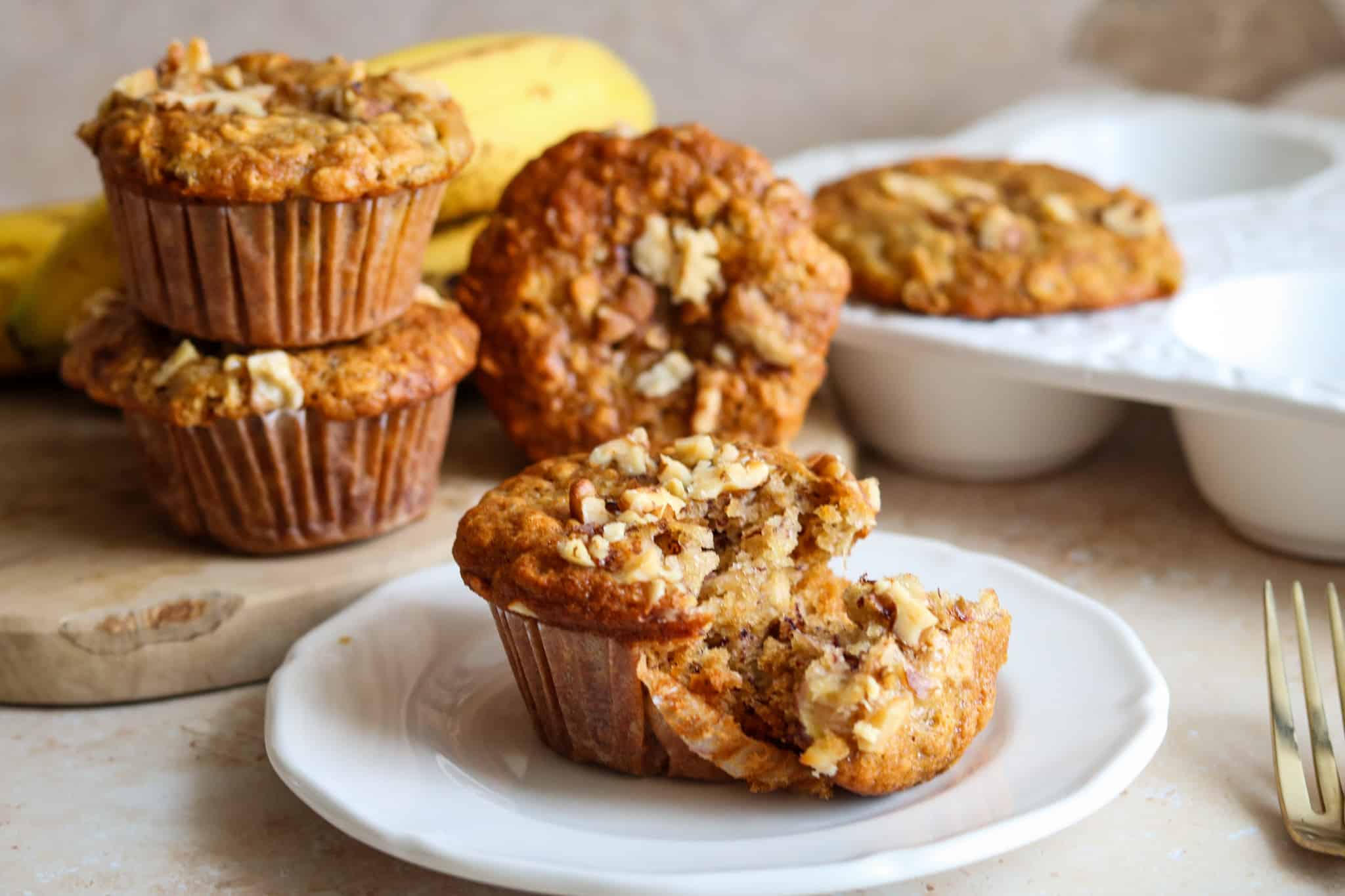 banana and oat muffins on white plate with bananas in the background