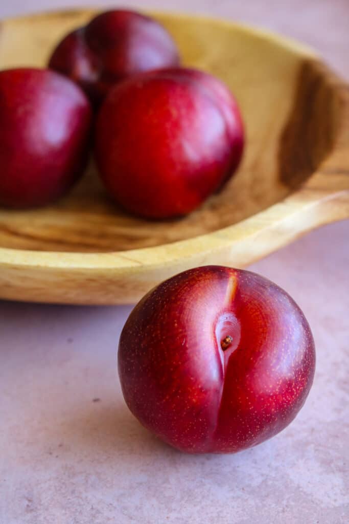 red plums in wooden bowl 