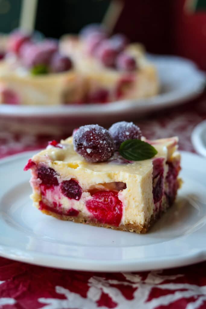 Cranberry orange cheesecake bars on white plate