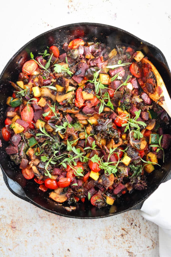 Vegetable hash with sweet potatoes and micro cilantro on black skillet