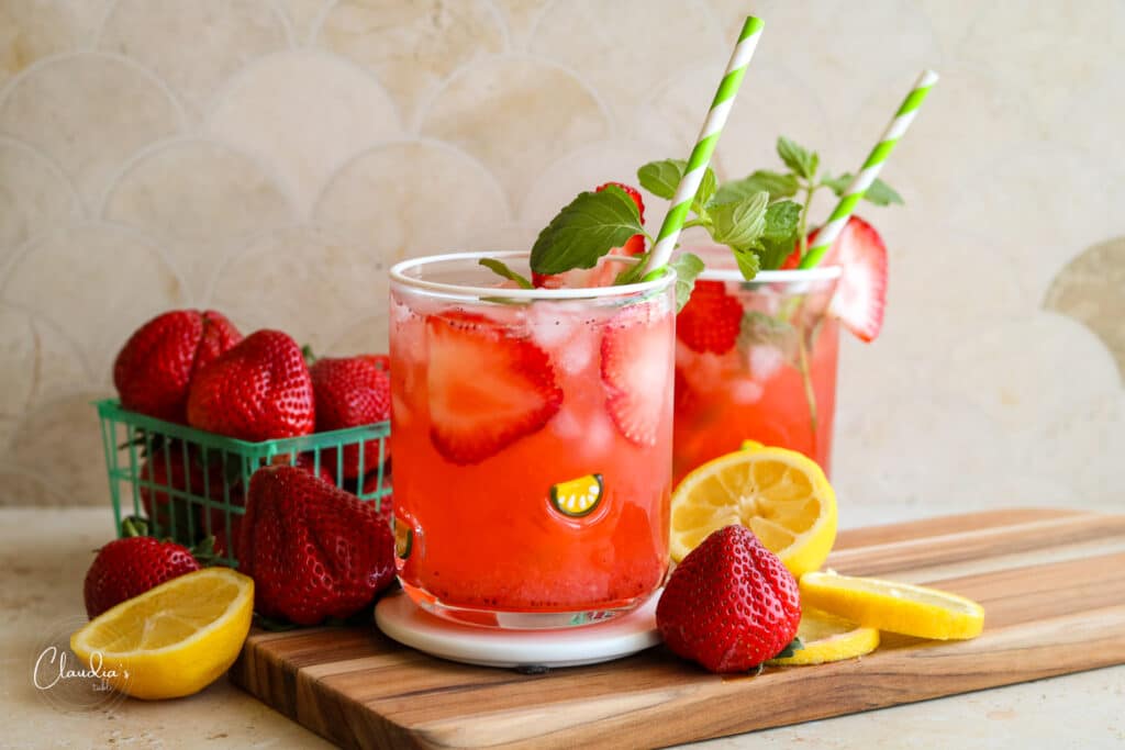 horizontal image of lemonade on board surrounded by strawberries and lemons