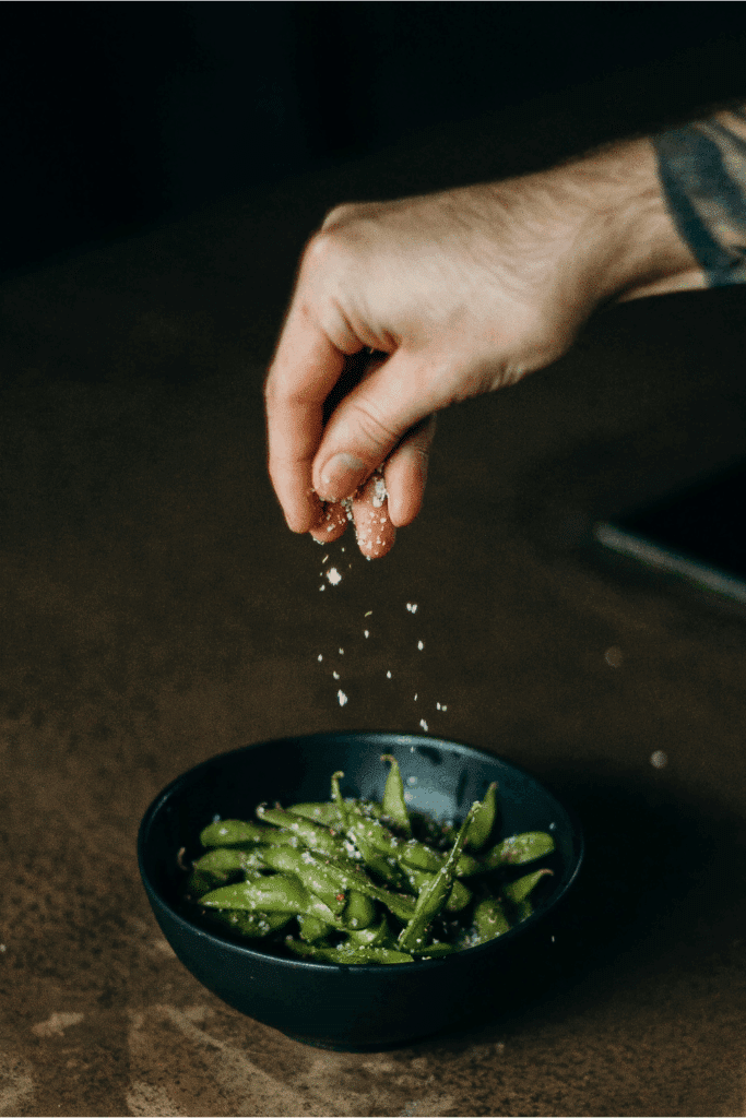 sprinkling salt on edamame 