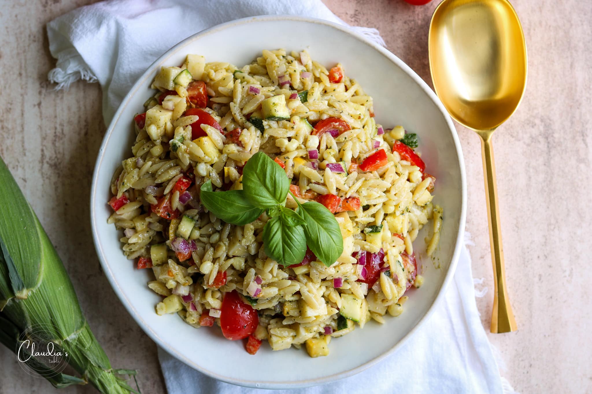 orzo pesto pasta salad in white bowl garnished with basil.