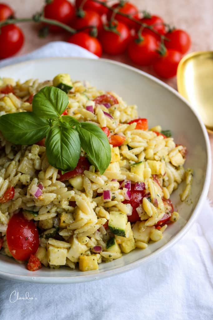 orzo pesto salad close up with basil garnish in white bowl 