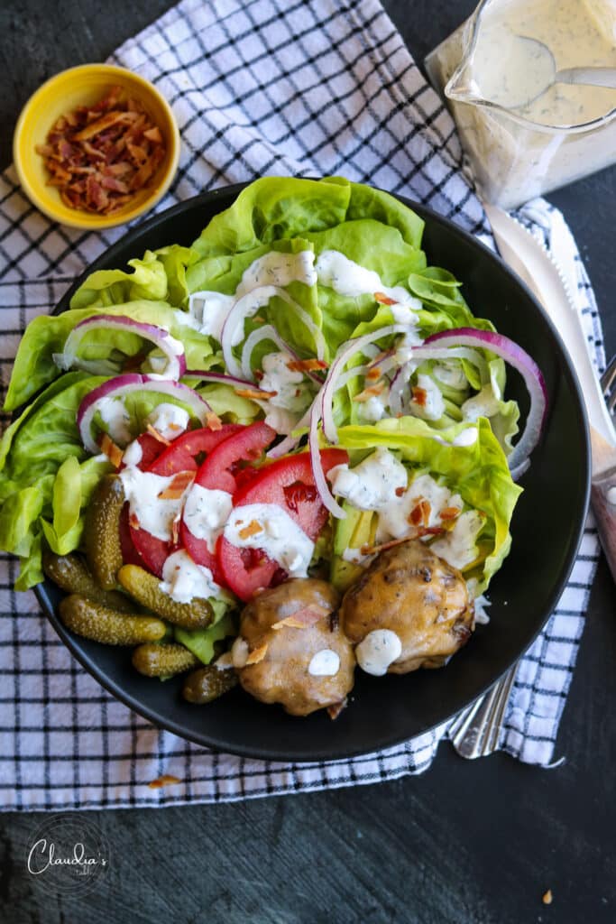 quick cheeseburger salad bowl with bacon in a black bowl. 