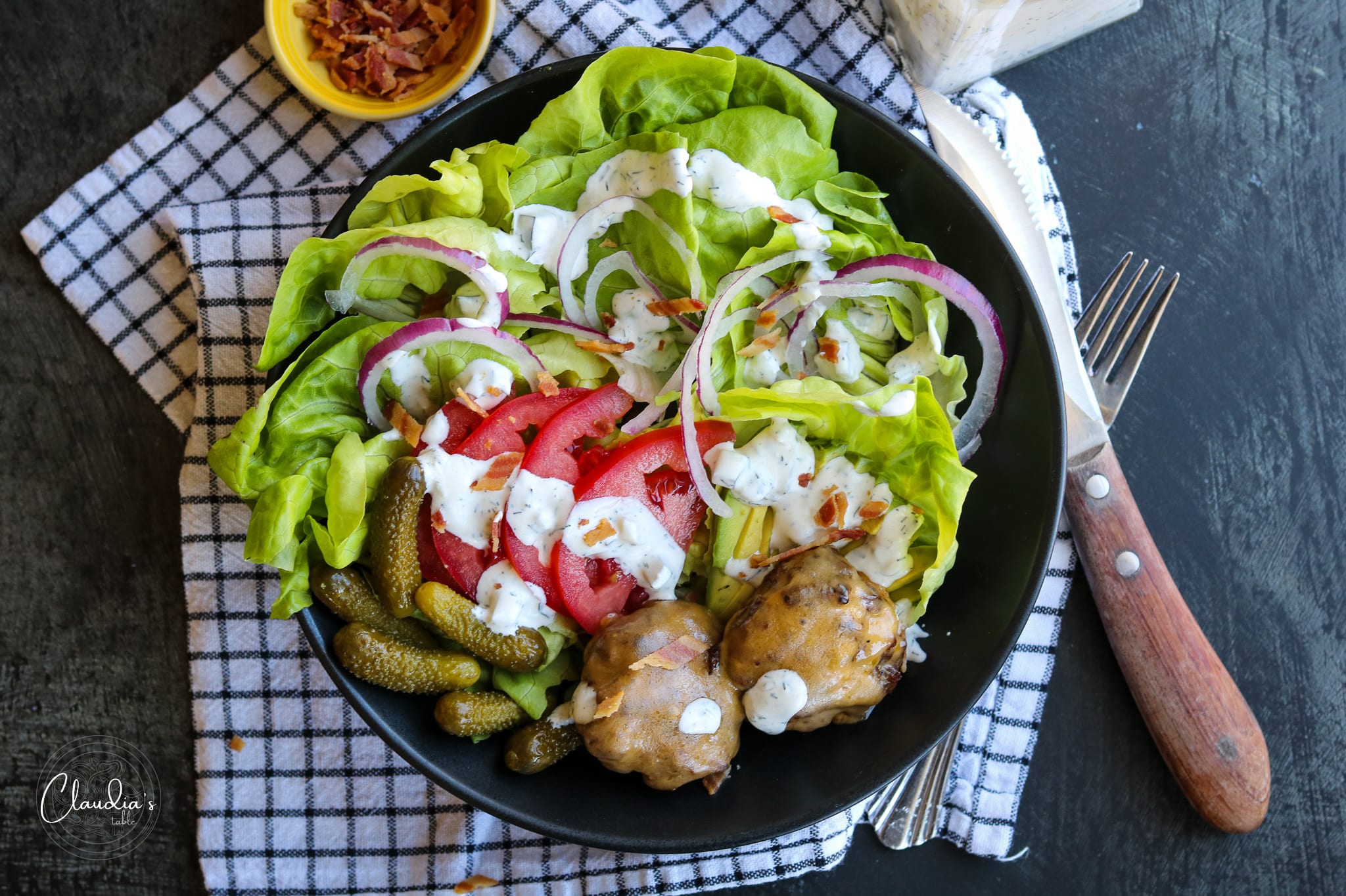 top view of cheeseburger salad with bacon pieces and dill pickle dressing