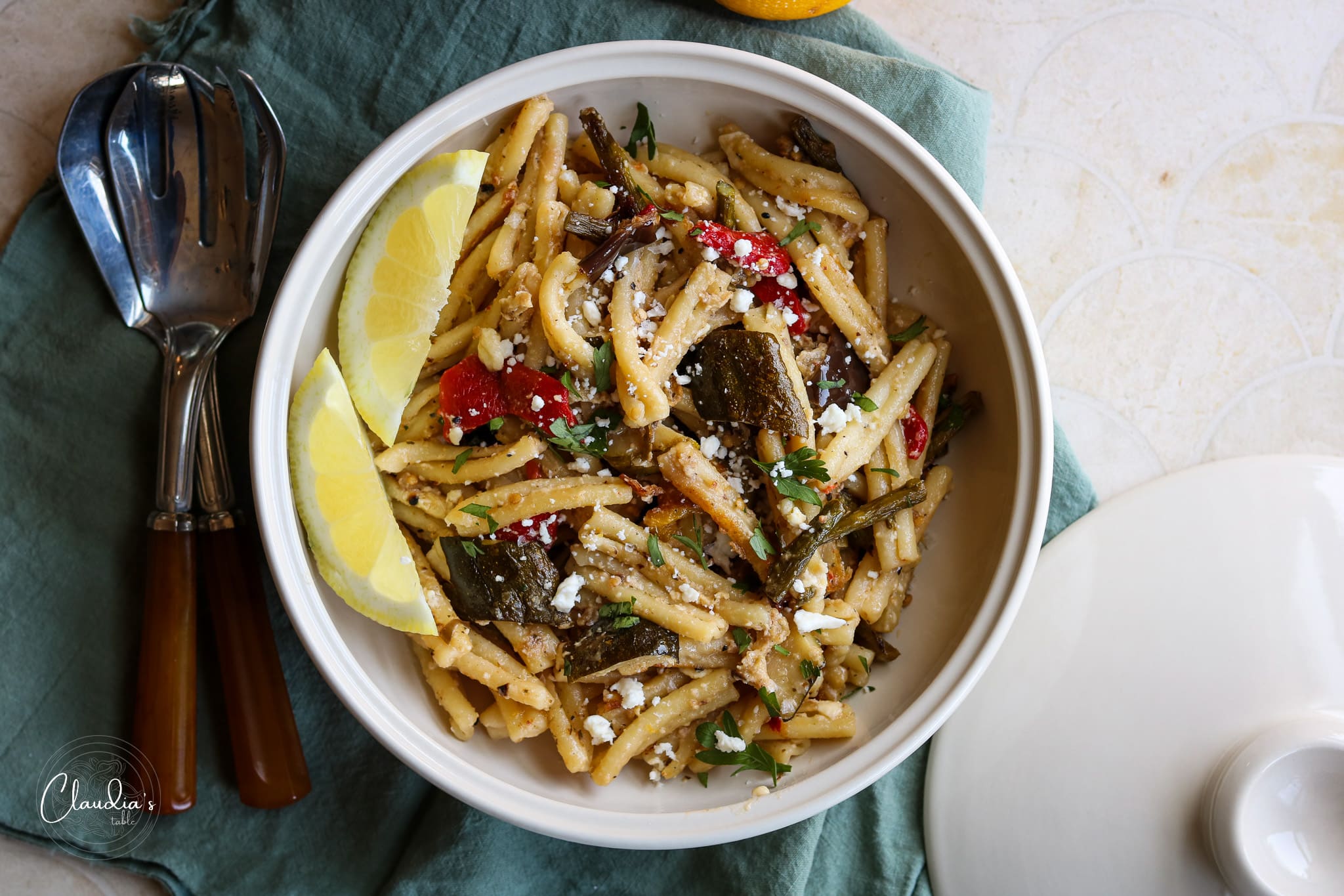 grilled vegetable pasta with feta and lemon in white bowl and green napkin